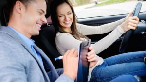 Driving instructor evaluating student in car.