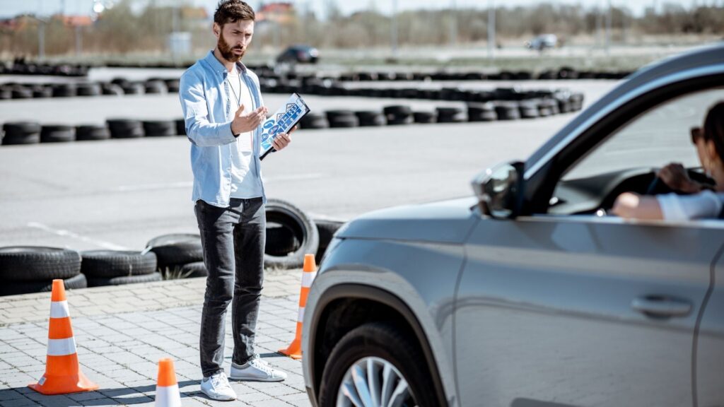 Driving instructor teaching student in car park.