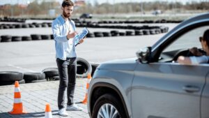 Driving instructor teaching student in car park.